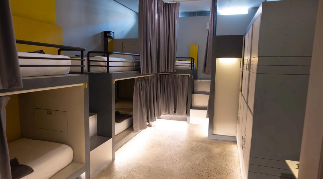 A picture of a hostel room in Siem Reap with many comfortable looking bunk beds with cozy floor lighting 