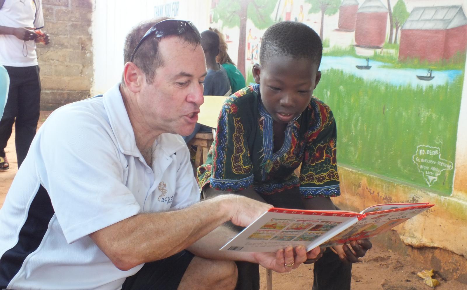 Un volontaire lit un livre à un enfant dans le cadre d'une mission de volontariat pour seniors