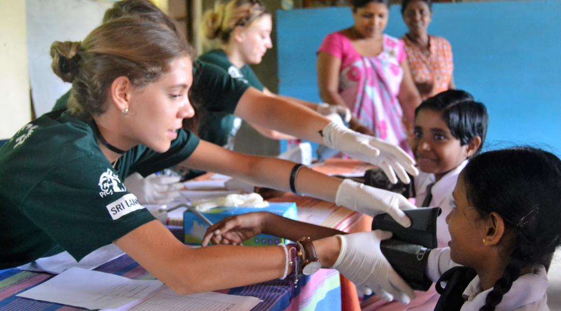 A clinical volunteer abroad measures the blood pressure of a young child in Sri Lanka.