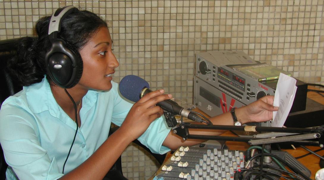 En tjej pratar i radio under hennes praktik på en radiostation utomlands.