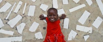 In an project volunteering with children in Tanzania a child smiles outside a care centre.