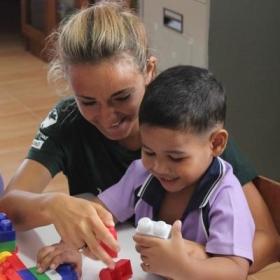A volunteer working abroad with children spends time building blocks with a child to improve early childhood development.