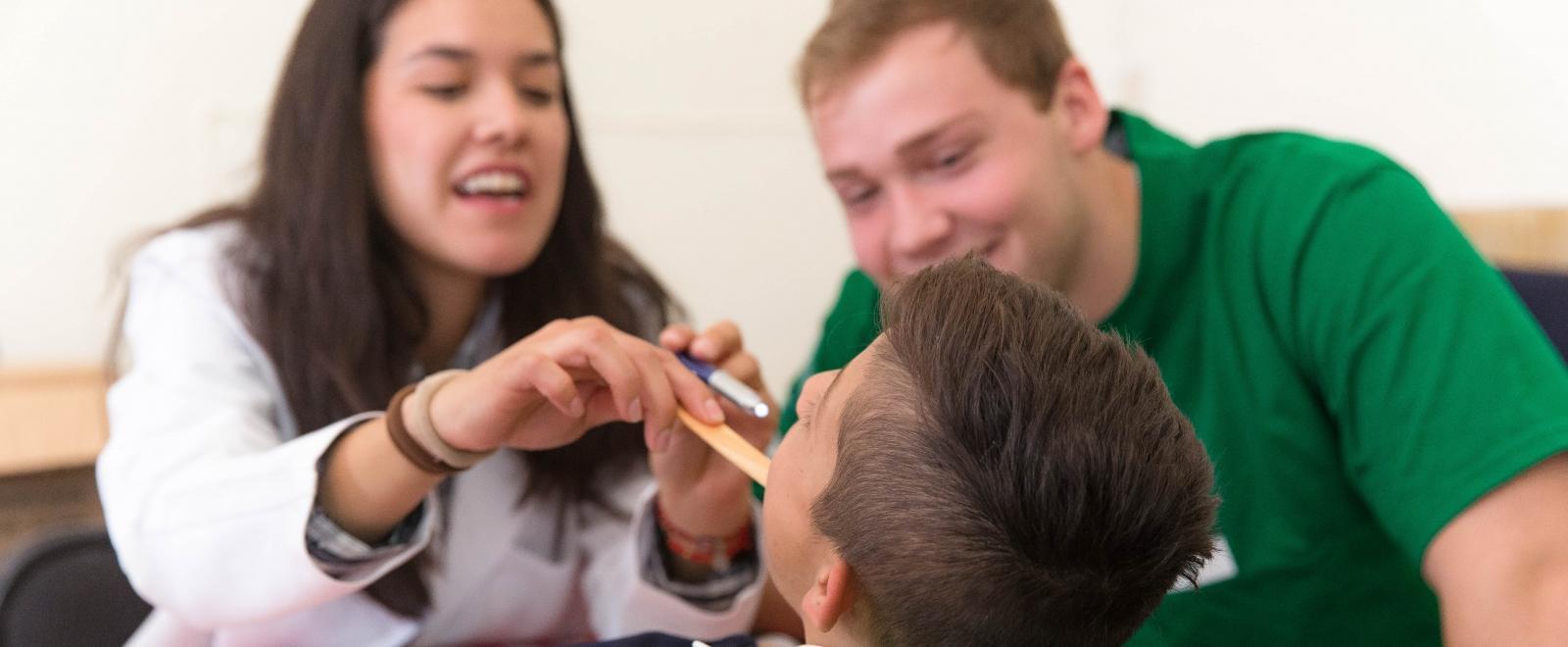 Interns examine a boy during a health screening outreach on one of our medical placements abroad.