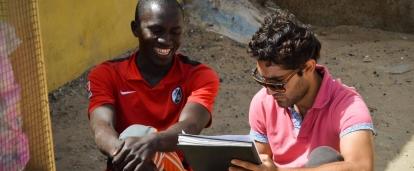 A Senegalese beneficiary discusses his business with a student doing a Micro-finance internship abroad.