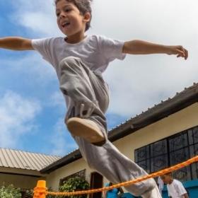 A young boy jumps over a rope during one of our Sports volunteering opportunities.