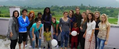 High school student volunteers doing building work in Nepal pose for a photo with young children and locals.  