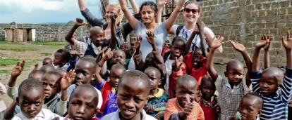 While doing community volunteer work in Ghana, teenagers take a group photo with children. 