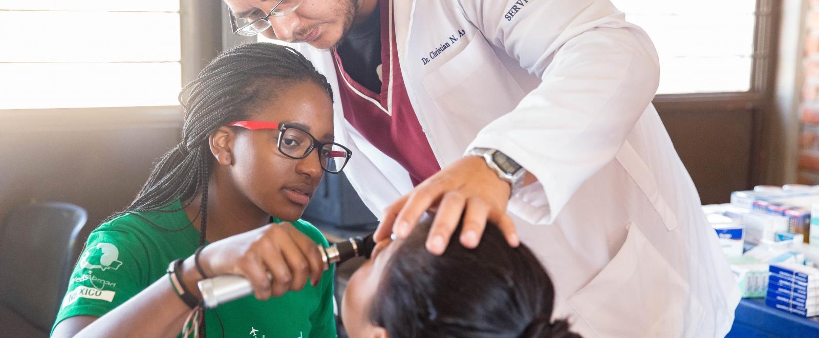 A Projects Abroad intern assists with checking a patient to gain internship work experience overseas. 