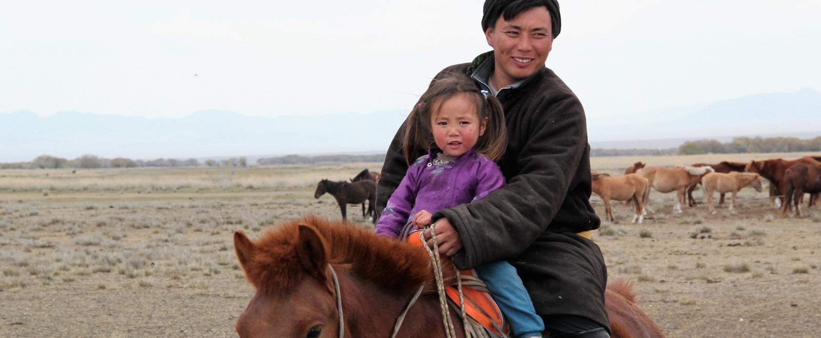 A father and daughter ride a horse at our Nomad Project for volunteers in Mongolia. 