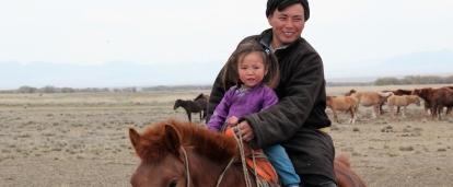 A father and daughter ride a horse at our Nomad Project for volunteers in Mongolia. 