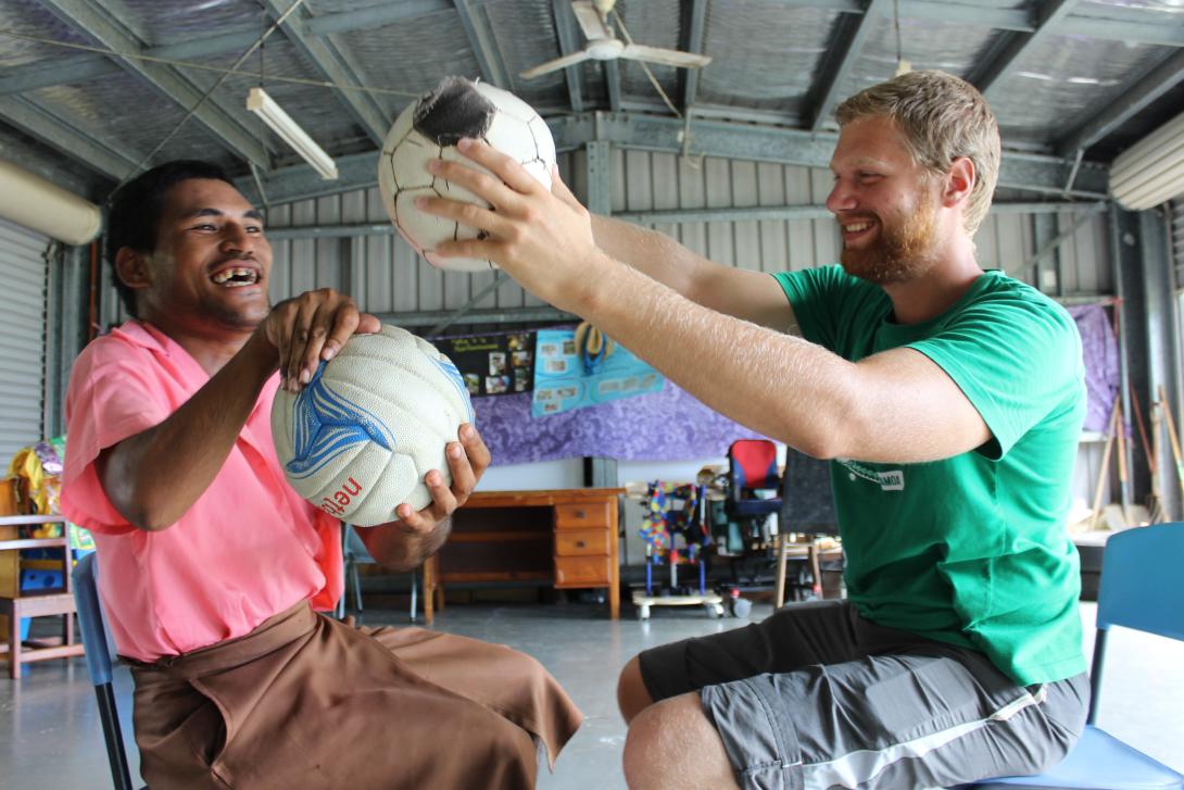 Voluntario de fisioterapia utilizando un balón como parte de una sesión terapéutica en un proyecto de voluntariado responsable.