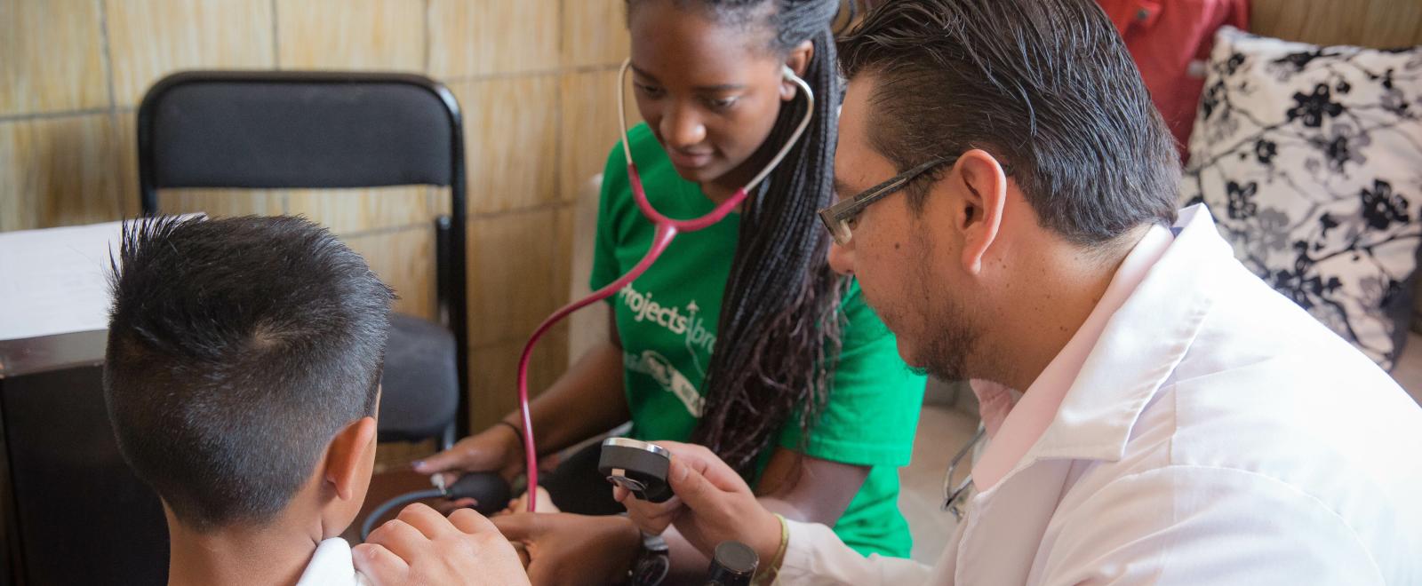 A student on a Spring Break Project in Mexico checks a child's pressure during a Public Health outreach