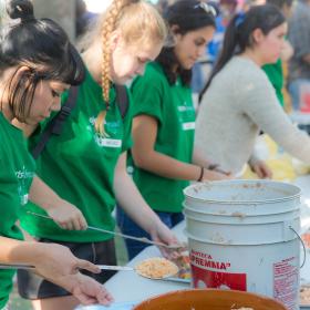 Refugee support volunteers serve a meal at a refugee camp in Mexico.