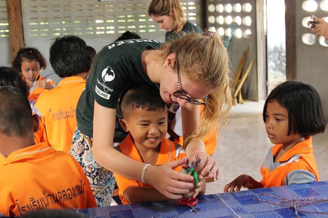 En un viaje solidario, una voluntaria de Educación en Tailandia ayuda a los niños en una lección de arte.