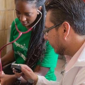 A student on a Spring Break Project in Mexico checks a child's pressure during a Public Health outreach