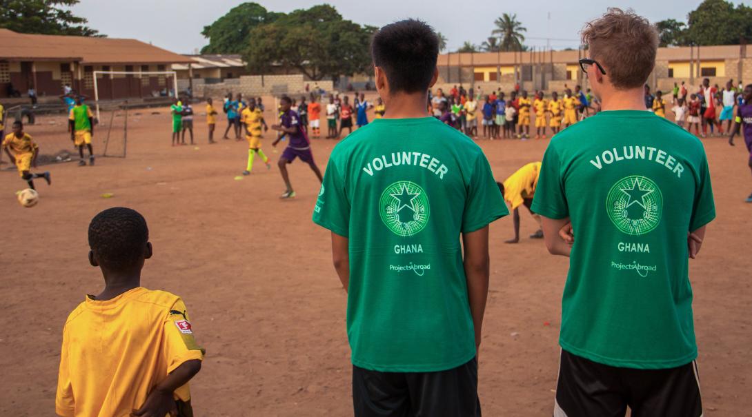 teen volunteers coaching and playing soccer with school children.
