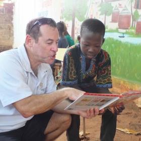 Voluntario mayor de 50 años ayudando a leer a un niño. 