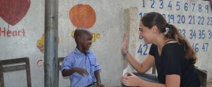 A Childcare volunteer in Ghana offers a child a high five for successfully completing an educational task. 