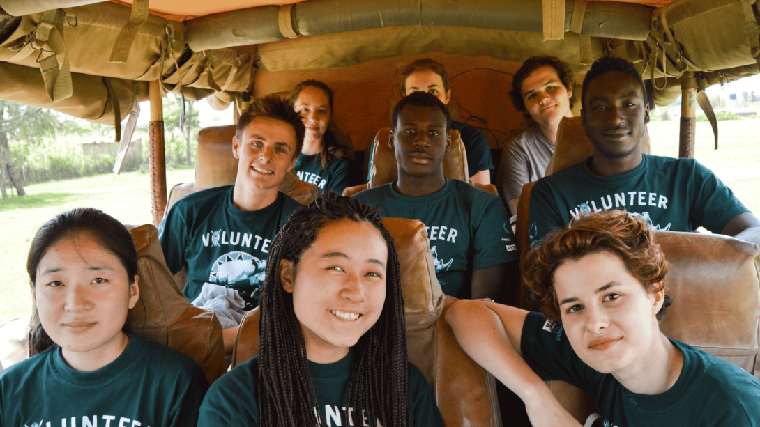 A group of conservation volunteers have their picture taken in a jeep