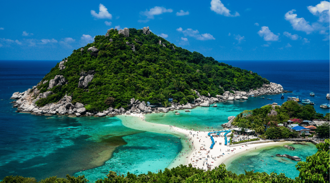 A landscape image of the tropical island of Koh Tao with crystal clear beaches and tourists 